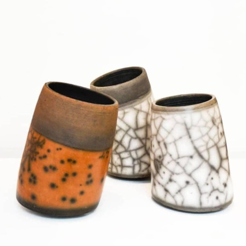 Three ceramic pots with unique textures and colors on a white background