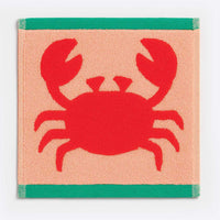 Square woven mat with a red crab design on a peach background