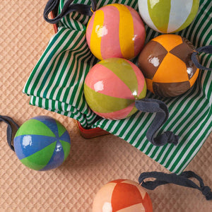 Colorful striped balls on a green and white striped bag on a beige surface