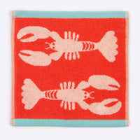 Red towel with pink lobster design on a white background